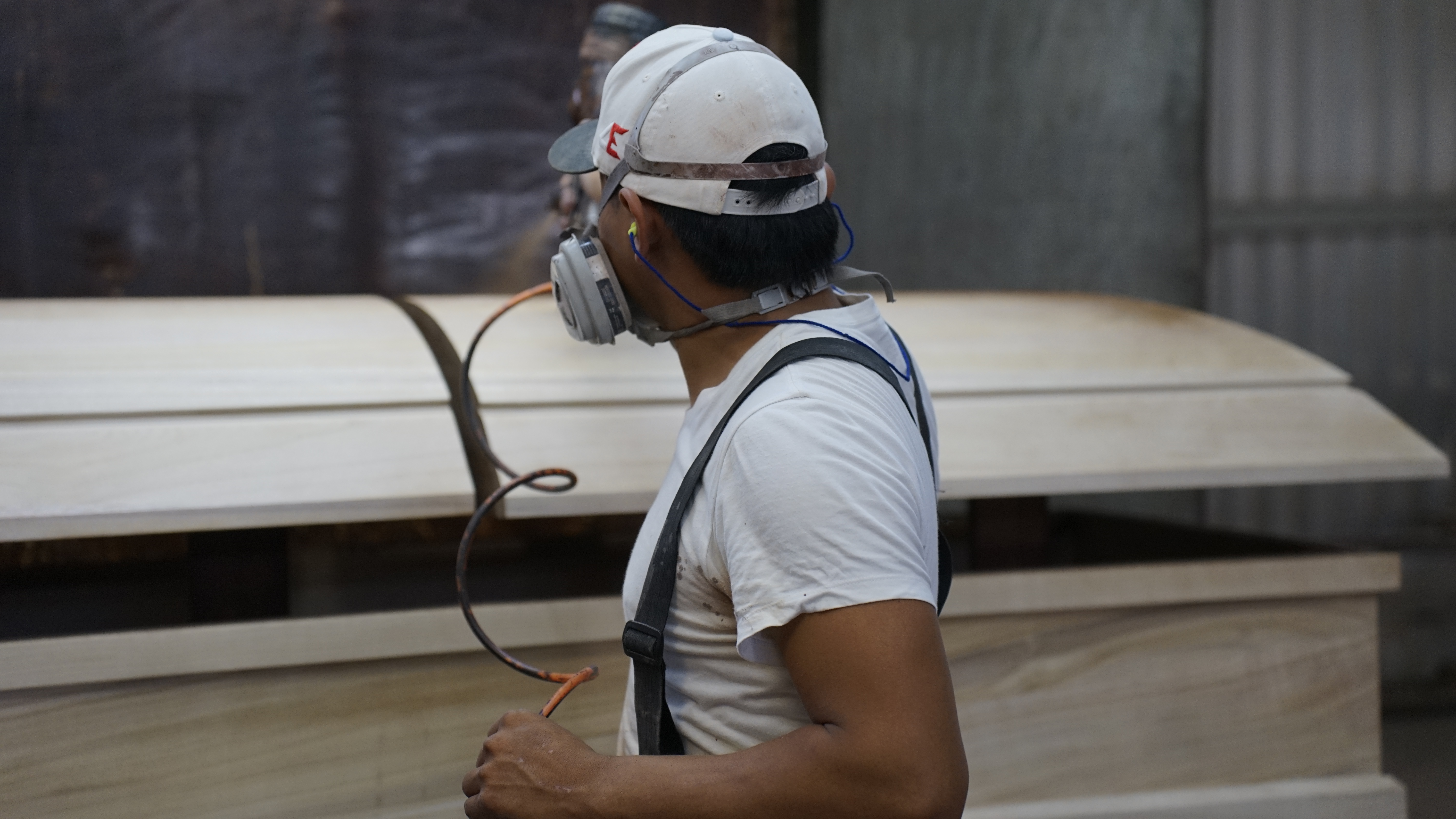 Row of casket bodies on finishing rails after base stain application